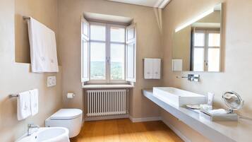 Ein modernes Badezimmer mit Fenster, Toilette, Waschbecken und großem Spiegel.
