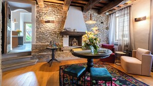 Un interior acogedor con una pared de piedra, una chimenea, una mesa redonda con un jarrón de flores y un área de estar confortable.