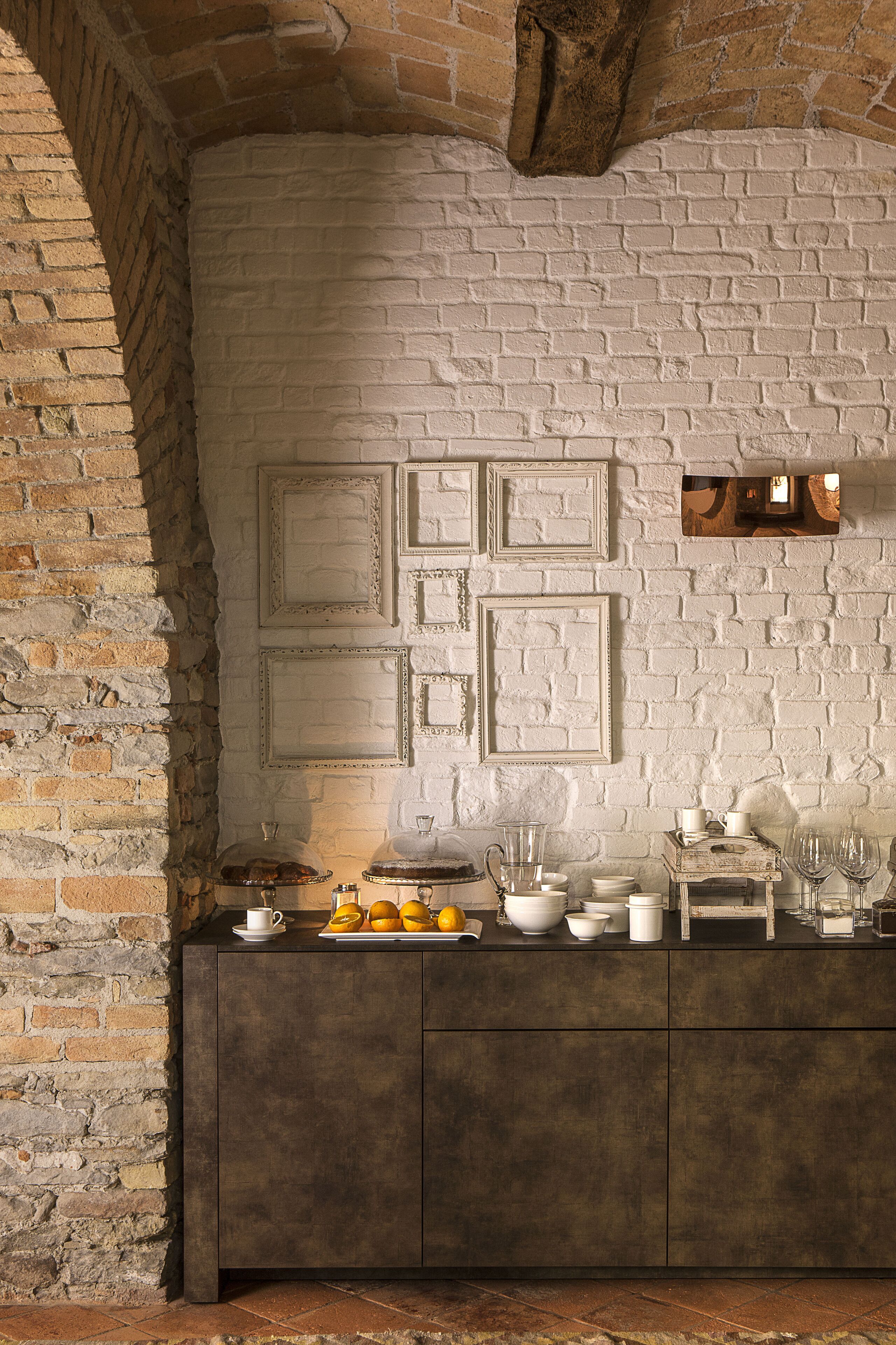 A rustic kitchen with exposed brick walls, a wooden cabinet, and various kitchen items.