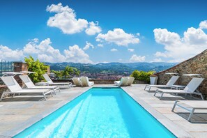 A rooftop pool with lounge chairs and a view of the countryside.