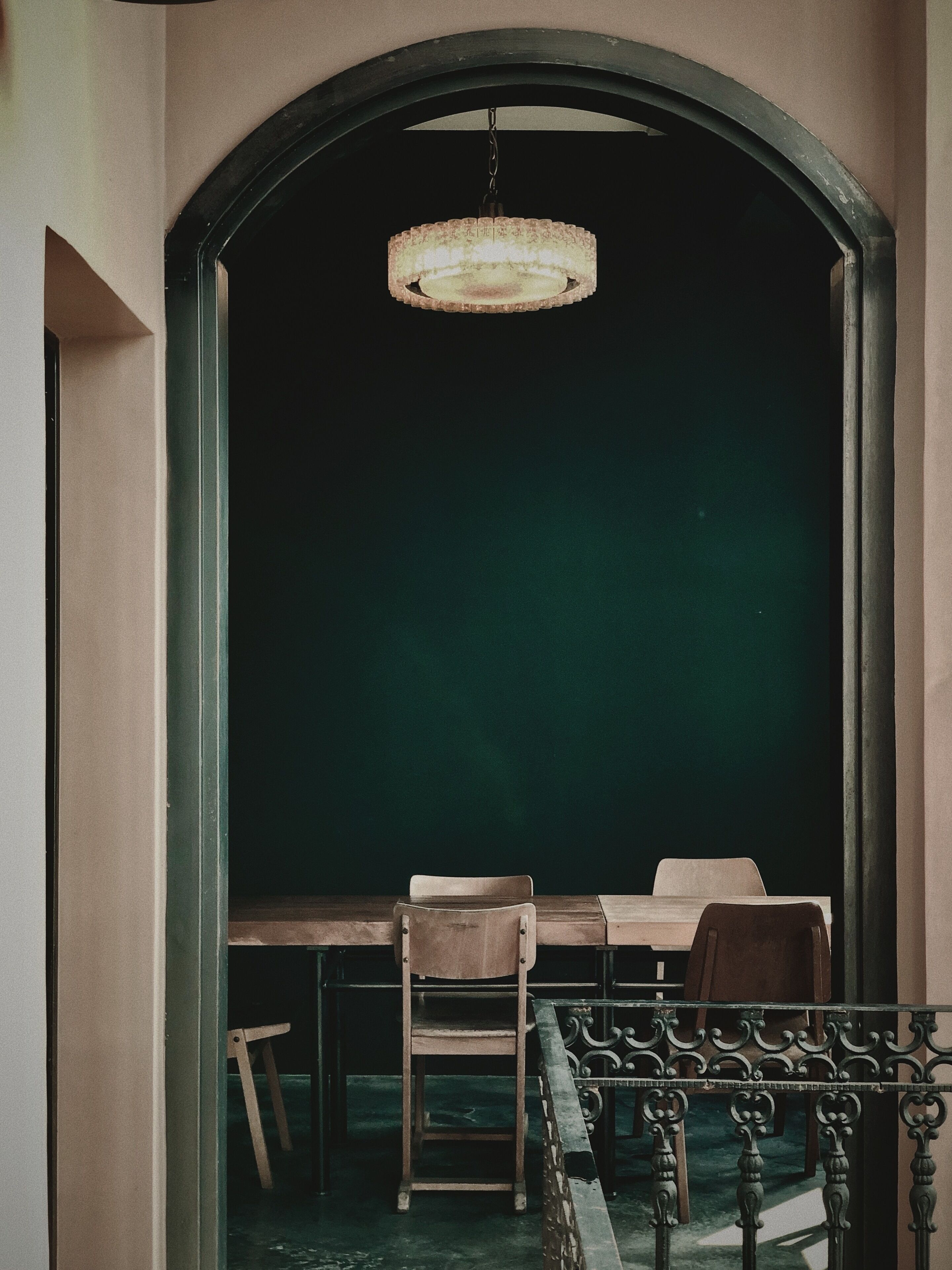 A room with a dark green wall, a wooden table, and two chairs.