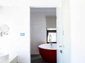 A modern bathroom with a white sink, a red bathtub, and a mirror on the wall. - Taikoo home (Tainan)