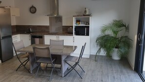 A compact kitchen with a refrigerator, dishwasher, microwave, and a dining table with chairs. - PORTICCIO QUIET AND CLIMATE VILLA 5 MIN FROM FOOT OF AGOSTA BEACH (Albitreccia)