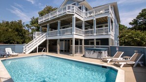 A two-story house with a swimming pool, a covered patio, and a staircase leading to the upper level.