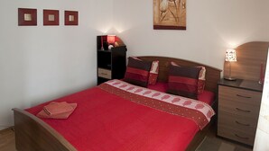 Een slaapkamer met een bed, nachtkastjes, een wandairconditioner en een schilderij.