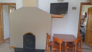 Un comedor con una mesa y sillas, un televisor montado en la pared y una chimenea.