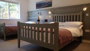 A bedroom with a wooden bed, a window, and a painting on the wall. - Ballyvaughan Cottage No 4 (Ballyvaughan)
