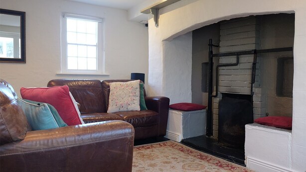 A living room with a fireplace, leather sofas, and a patterned rug. - Ballyvaughan Cottage No 4 (Ballyvaughan)