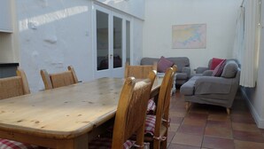 A dining area with a wooden table and chairs, a grey sofa, and a map on the wall. - Ballyvaughan Cottage No 4 (Ballyvaughan)