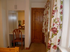 Um quarto com porta de madeira, uma cadeira e uma mesa pequena.