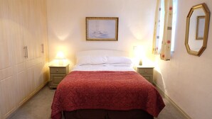 A bedroom with a bed, two bedside tables, a nightstand, a wardrobe, and a framed picture on the wall. - Ballyvaughan Cottage No 2 (Ballyvaughan)