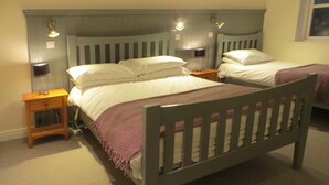 Un dormitorio con dos camas individuales, cabeceros de madera, lámparas de noche y una mesita de noche con lámpara.