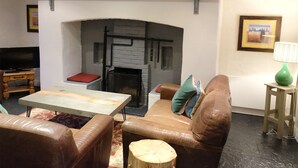 Una sala de estar con chimenea, muebles de cuero y televisor.
