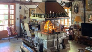 Een rustiek interieur met een stenen openhaard, houten balken en een gezellige zithoek.