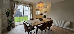 A dining area with a large table, chairs, a potted plant, and a view of the outside. - Bunratty Town House No 14 (Bunratty)