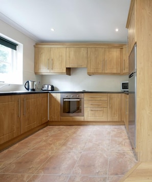 A modern kitchen with wooden cabinets, a built-in oven, and a stainless steel refrigerator.