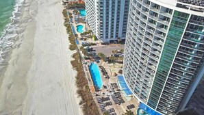 Ein Hochhaus-Hotel mit Poolbereich, Strandlage und mehreren Balkonen.