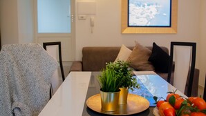 A modern living room with a sofa, a coffee table with a plant and tomatoes, and a framed picture on the wall. - Casa King - Welchome (Cannobio)