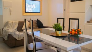 A modern living room with a sofa, a coffee table with a potted plant and fruit bowl, and a flat-screen TV mounted on the wall. - Casa King - Welchome (Cannobio)