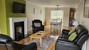 A living room with a fireplace, leather sofas, a coffee table, and a dining area with a table and chairs.