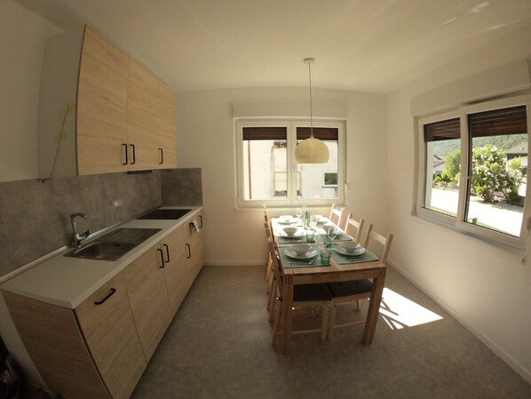 A modern kitchen with wooden cabinets, a built-in stove, and a dining area with a table set for four.