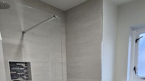 A modern bathroom with a shower, a toilet, and a window.