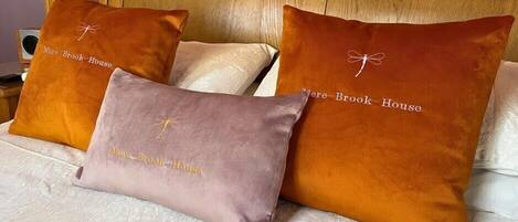 A bed with three pillows, two of which have 'More Brook House' embroidered on them.