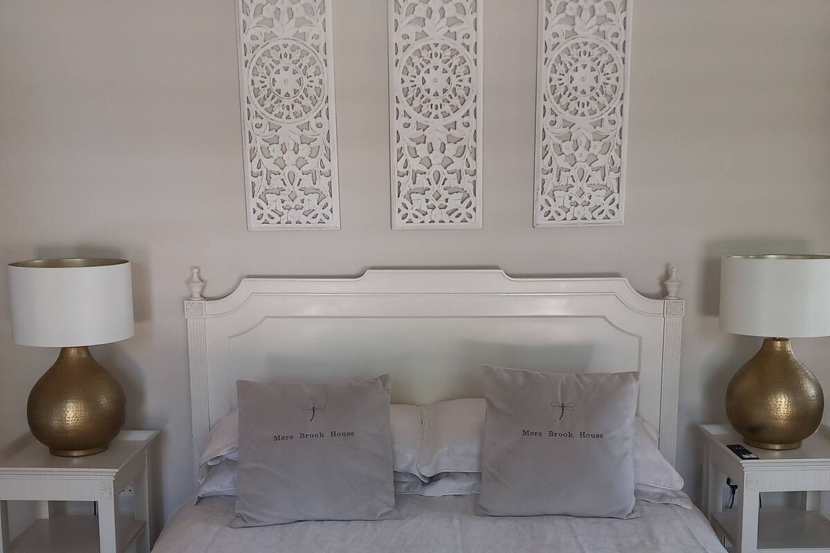 A neatly made bed with two pillows and a headboard, flanked by two bedside tables with lamps.