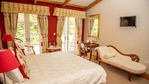 A bedroom with a large bed, a chaise lounge, a desk, and a chair. - Mere Brook House (Wirral)