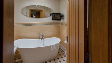 A bathroom with a freestanding bathtub, a mirror, and a towel rack.