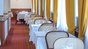 A restaurant with tables set for dining, featuring white tablecloths and wicker chairs.