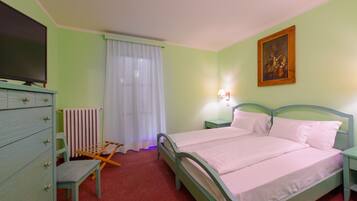 A bedroom with a bed, a dresser, a chair, a radiator, a television, and a painting on the wall.