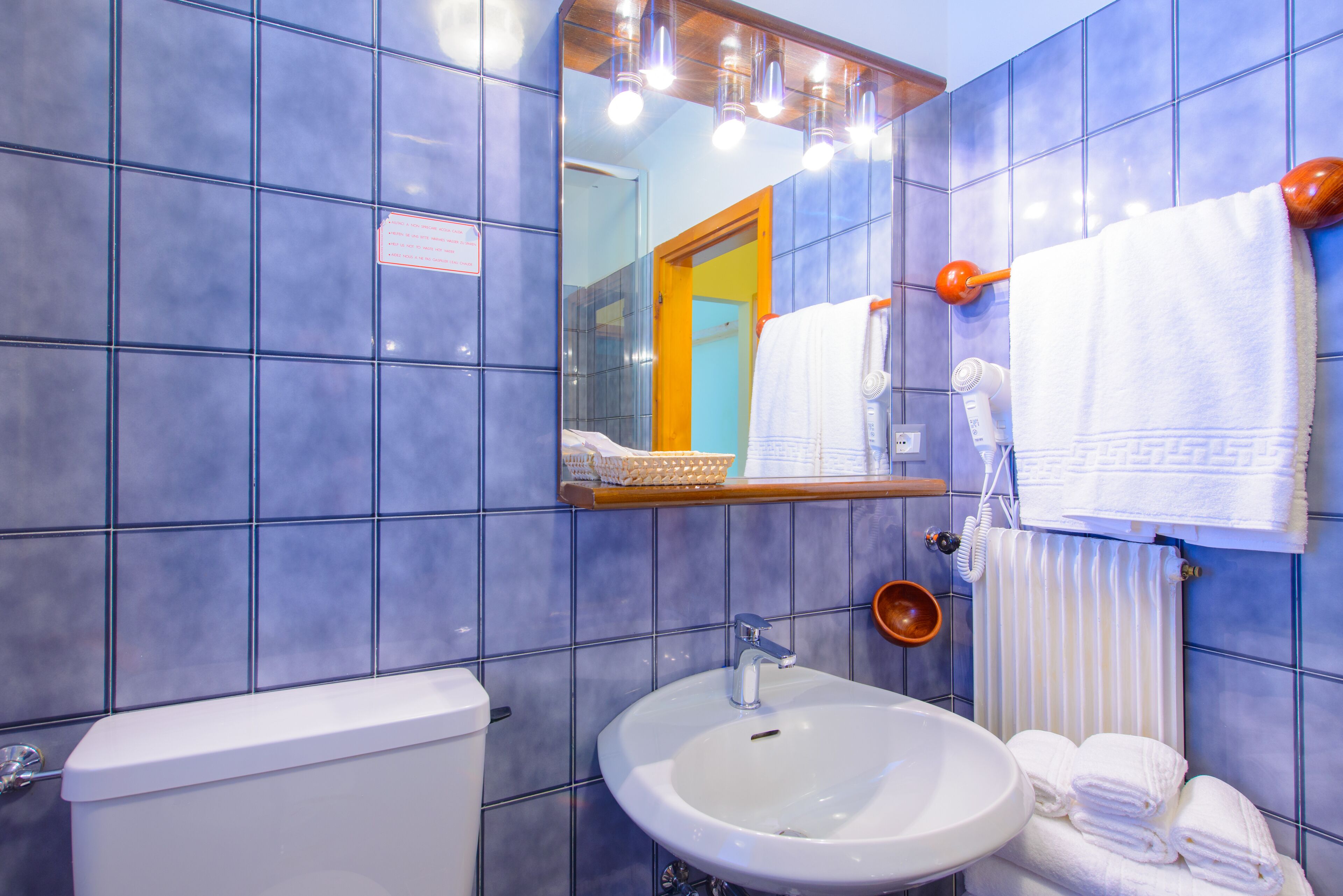 A bathroom with a toilet, sink, mirror, and towel rack.