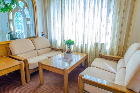 A cozy room with a sofa, armchair, and a small table with a plant. - Park Hotel Faloria (Canazei)