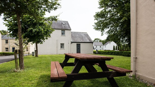 Una mesa de picnic en un área con césped y un edificio al fondo.