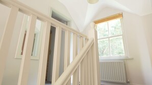 Valkoisilla kaiteilla varustetut portaat johtavat huoneeseen, jossa on ikkuna ja patteri.