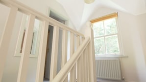 Een trap met witte leuningen die leidt naar een kamer met een raam en een radiator.