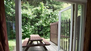 Een terras met een houten tafel en stoelen, omringd door een houten hek en weelderige beplanting.