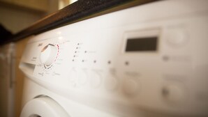A white washing machine with a control panel, including a dial and buttons. - Castle Gardens 3 bed 4052 (Bunratty)