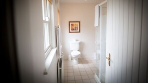 A narrow hallway leading to a bathroom with a toilet, a framed picture on the wall, and a light fixture above the toilet. - Castle Gardens 3 bed 4052 (Bunratty)