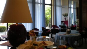 Una camera d'albergo con una grande finestra, una lampada, un tavolo con una cupola in vetro e una sedia.