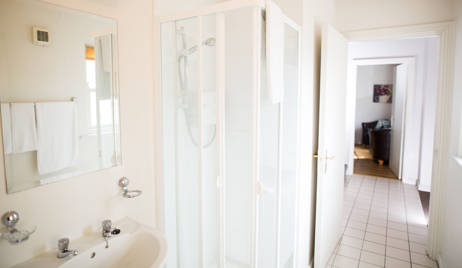 A bathroom with a sink, mirror, and shower.