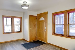 Una habitación con dos ventanas, una puerta de madera y un candelabro en el techo.