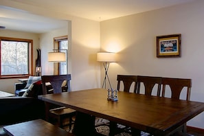 Un comedor con una mesa y sillas de madera, una lámpara y un cuadro en la pared.