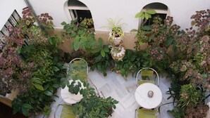 A patio area with a table and chairs, surrounded by various potted plants. - Hostal Alcazar I (Córdoba)