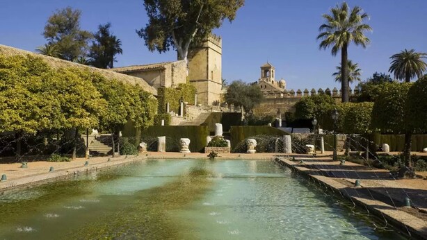 A historic building with a tower, a fountain, and a clear pool. - Hostal Alcazar I (Córdoba)
