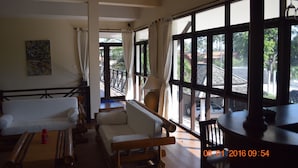 A spacious room with a large window, a sofa, a wooden table, and a painting on the wall. - 3 Bedroom pool villa 2 SDV023-By Samui Dream Villas (Koh Samui)
