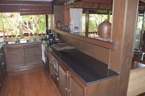 Une cuisine dotée d’un plan de travail noir, de meubles en bois et d’une fenêtre donnant sur un paysage verdoyant.