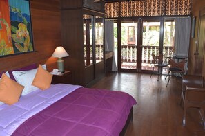 A hotel room with a bed, a nightstand, a lamp, a balcony with chairs, and a view of the outdoors. - 4 bedroom beachfront Villa 3 SDV024-By Samui Dream Villas (Koh Samui)
