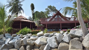 A resort with a large rock garden, a wooden structure with a thatched roof, and a balcony overlooking the garden. - 3 Bedroom Beach Front Villa with Private Pool - P3 SDV026-By Samui Dream Villas (Koh Samui)